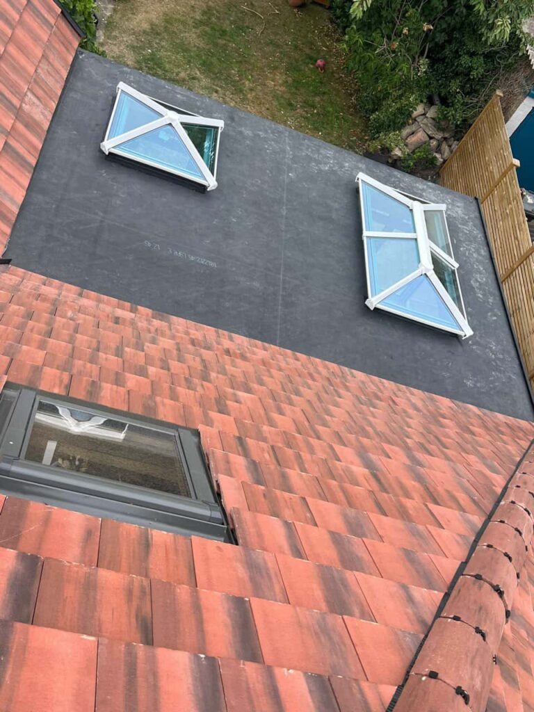 This is a photo taken from the roof ridge looking down a tiled pitched roof on to a flat roof. Works carried out by Braunstone Roofing Repairs
